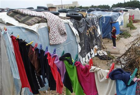 Syrian girl looks on as clothes are left hanging on a line at a refugee camp in the city of Tyre, in southern Lebanon