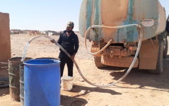 An aid worker delivers water to the Rukban camp in southern Syria near the Jordanian border